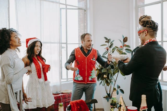 Ryhmä jouluasuisia ihmisiä juhlimassa juhlissa ja esittelemässä yhdessä veroton lahjan henkeä